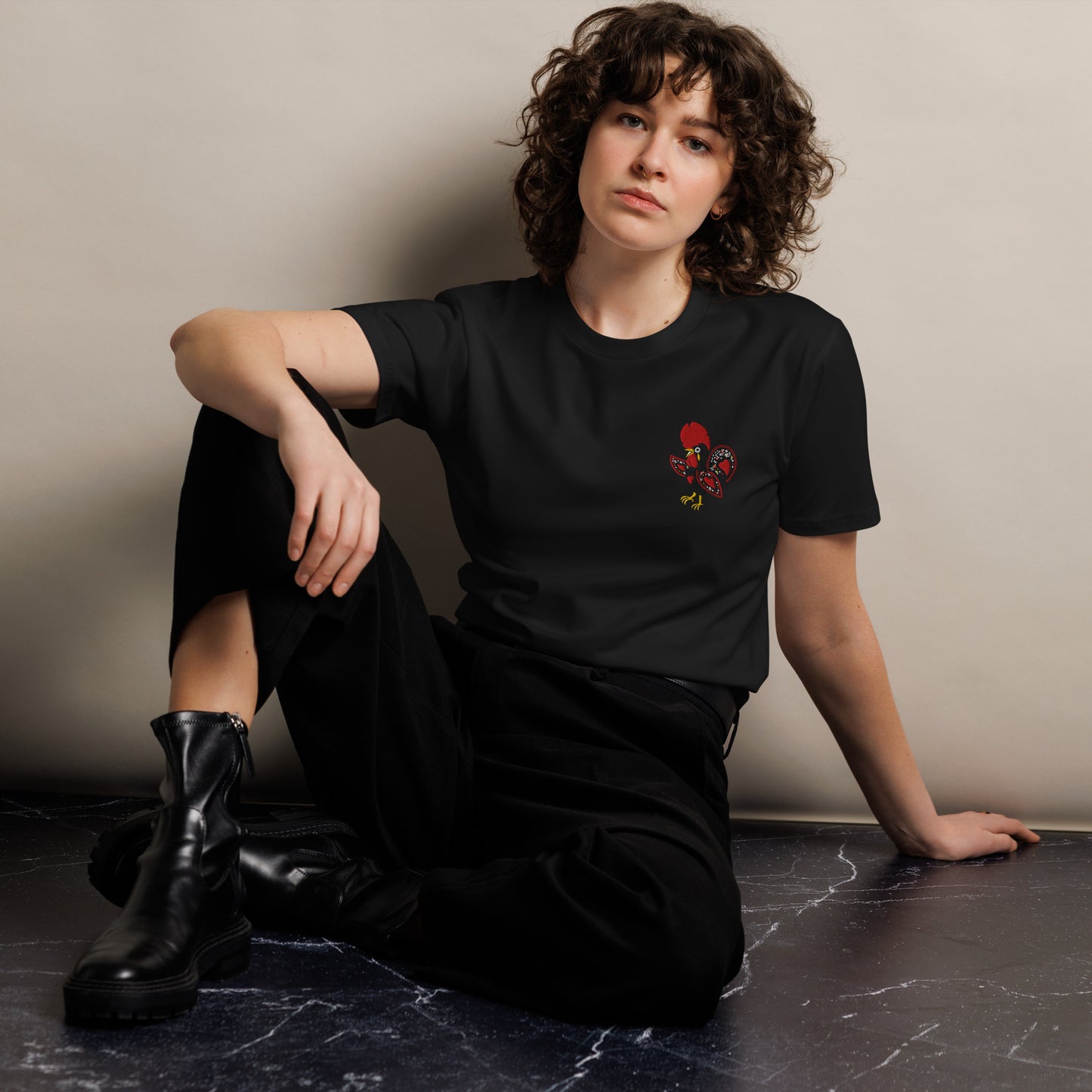 Close up of the Galo de Barcelos chest embroidery on a black RAIZ tee
